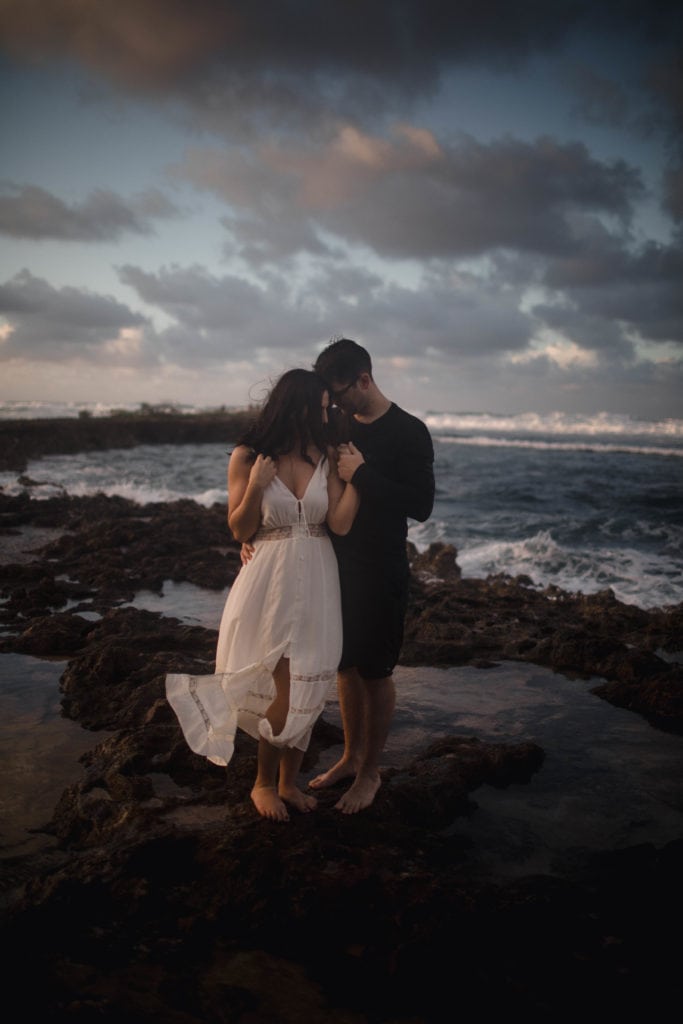 Couple on their honeymoon at the beach cuddling and taking honeymoon photos.