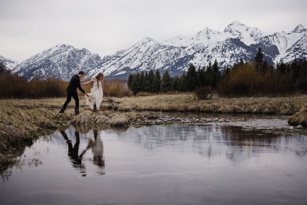 A bride and groom crossing Snake river at their Jackson Hole wedding venue.